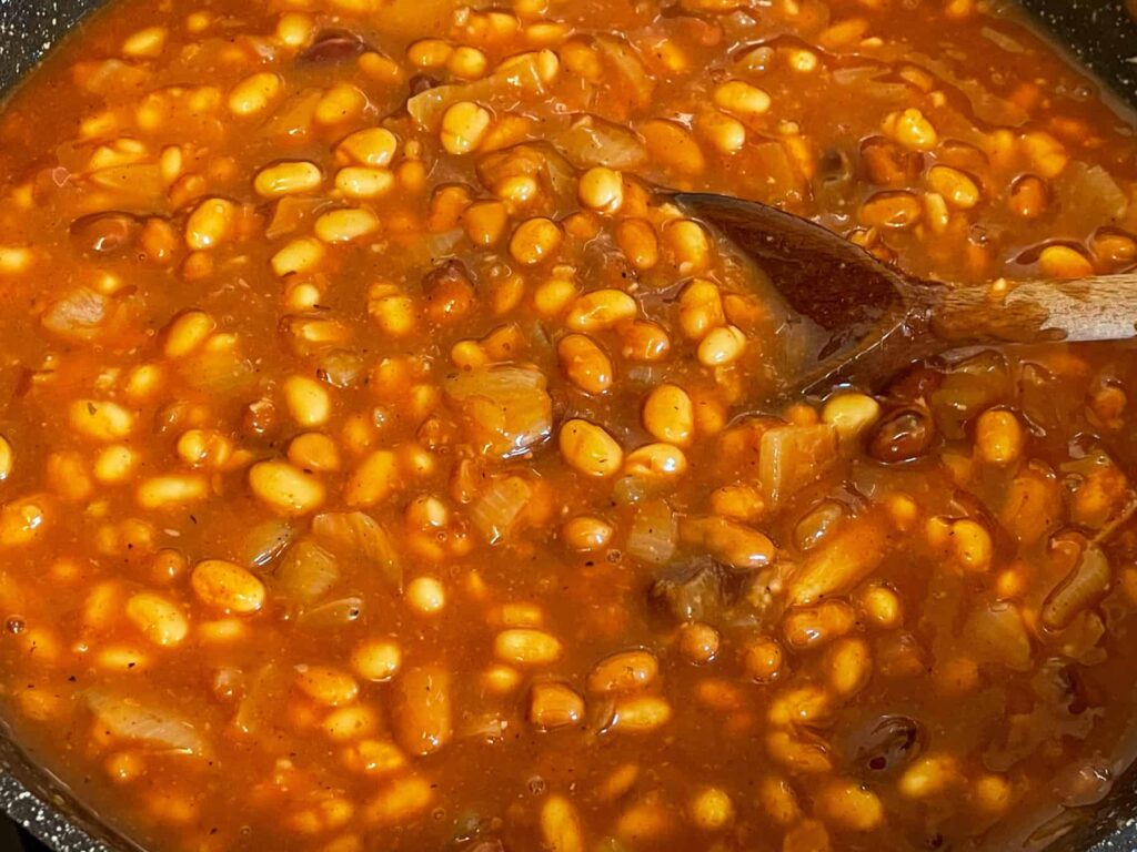Baked beans added to onion mix in skillet.