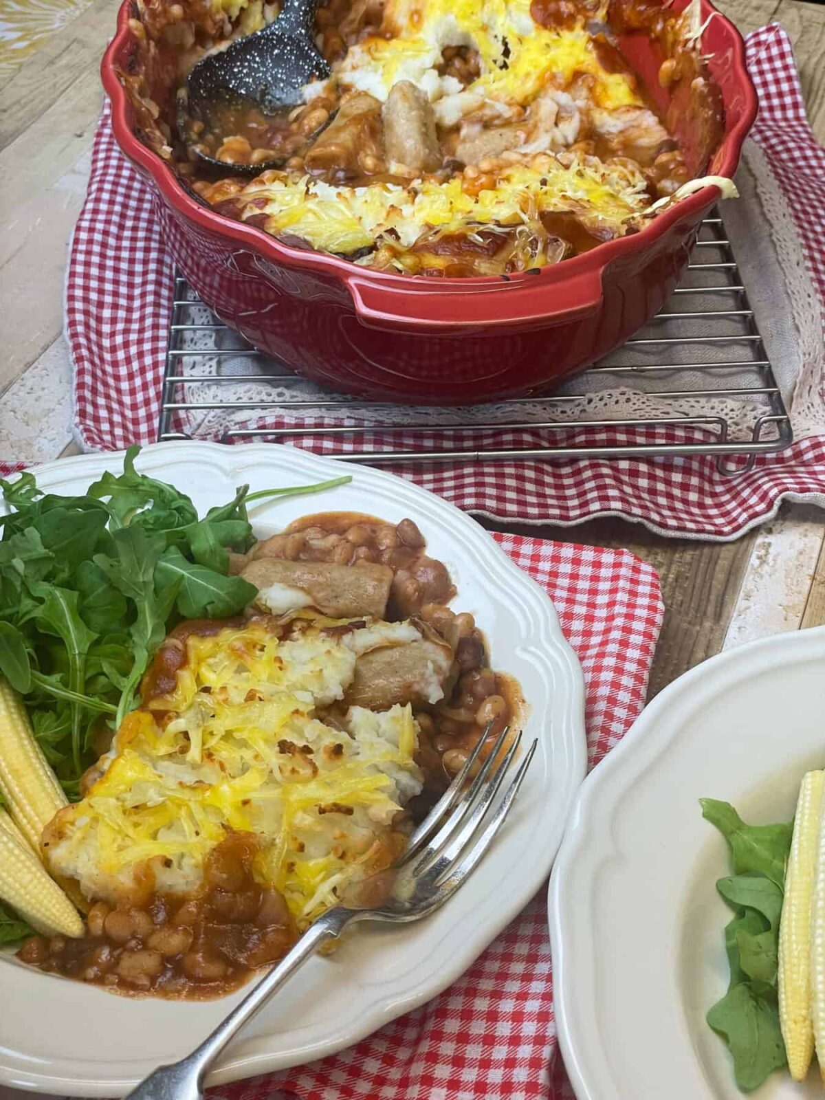 Cowboy pie served in white bowl with red check cloth, red pie dish in distance.