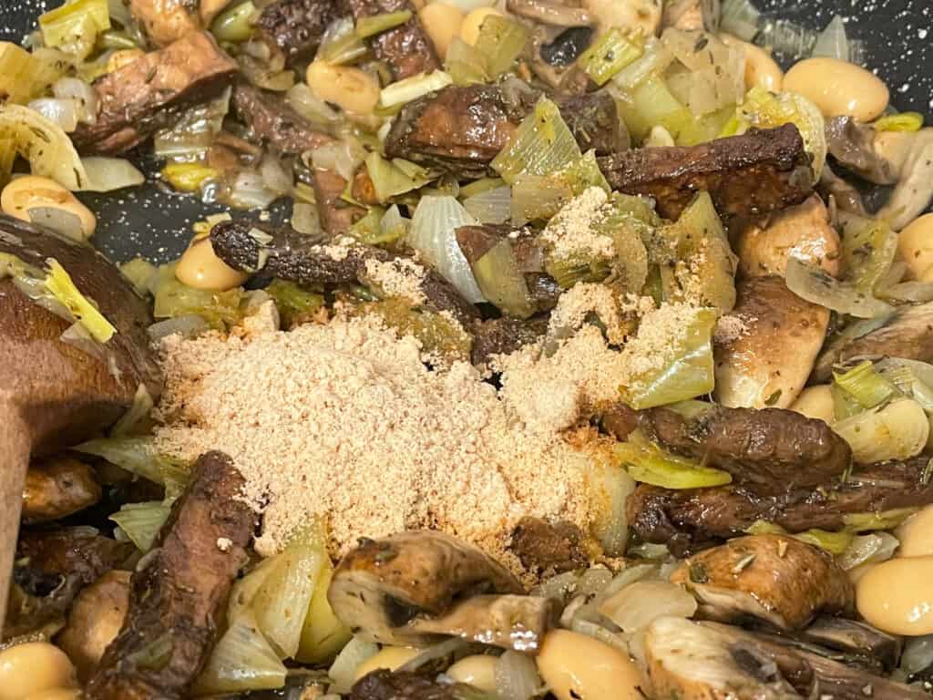 Gravy powder and herbs added to filling cooking in pan.