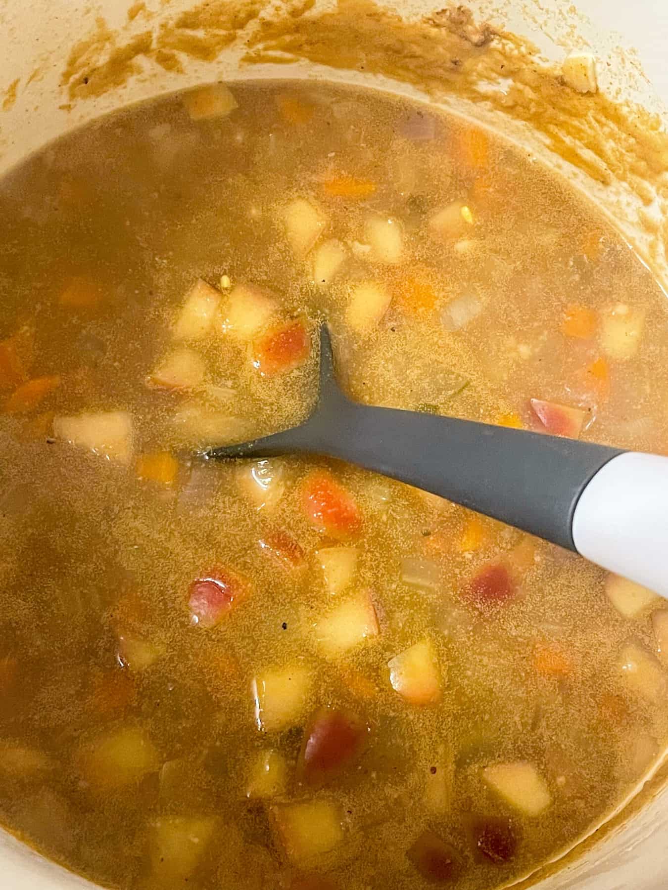 Soup cooked and ready to serve with grey soup ladle.