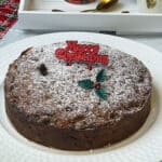 Christmas cake served on white cake plate with tea tray to side.