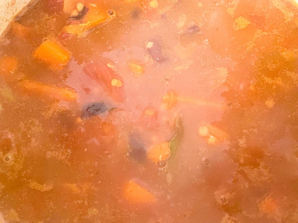 lasagna lentil veggie mix with veggie stock simmering in pan.