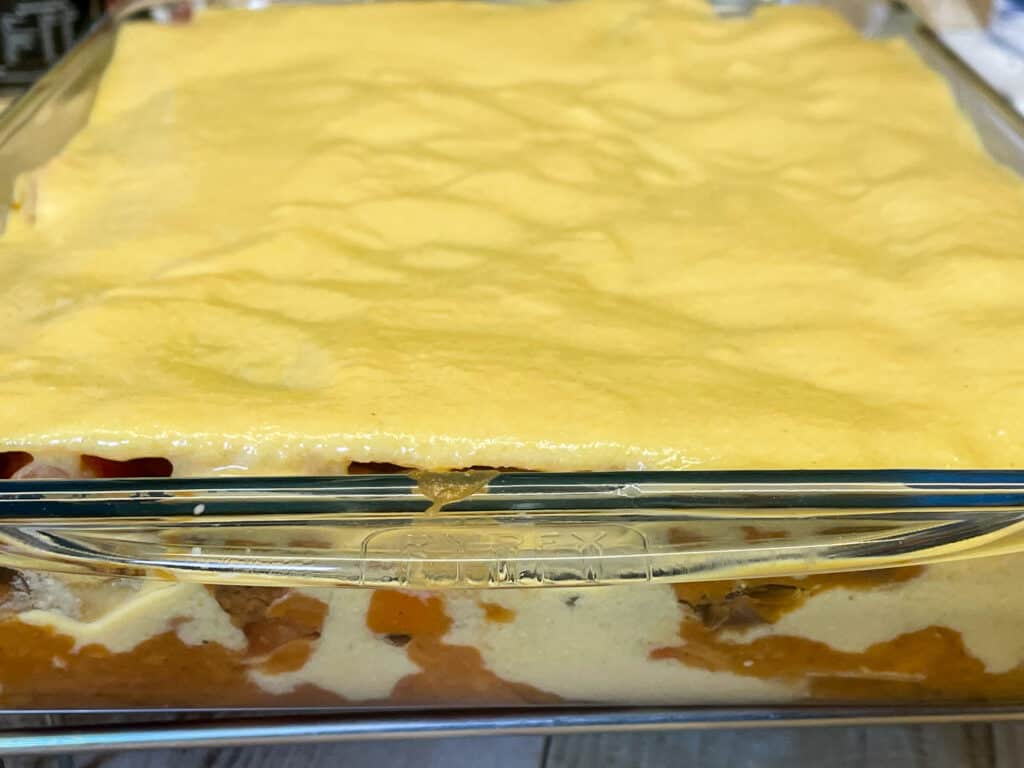 vegan cheese sauce spread over the lentil lasagna ready to bake.
