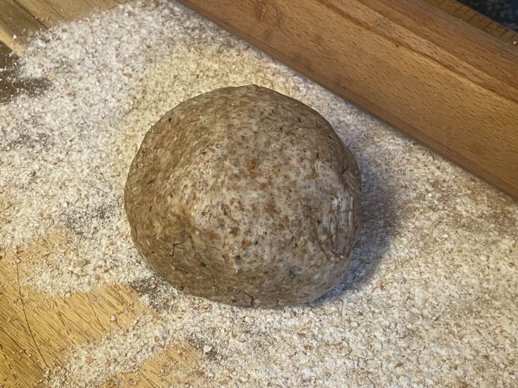 Pastry dough on a floured surface with rolling pin to side.