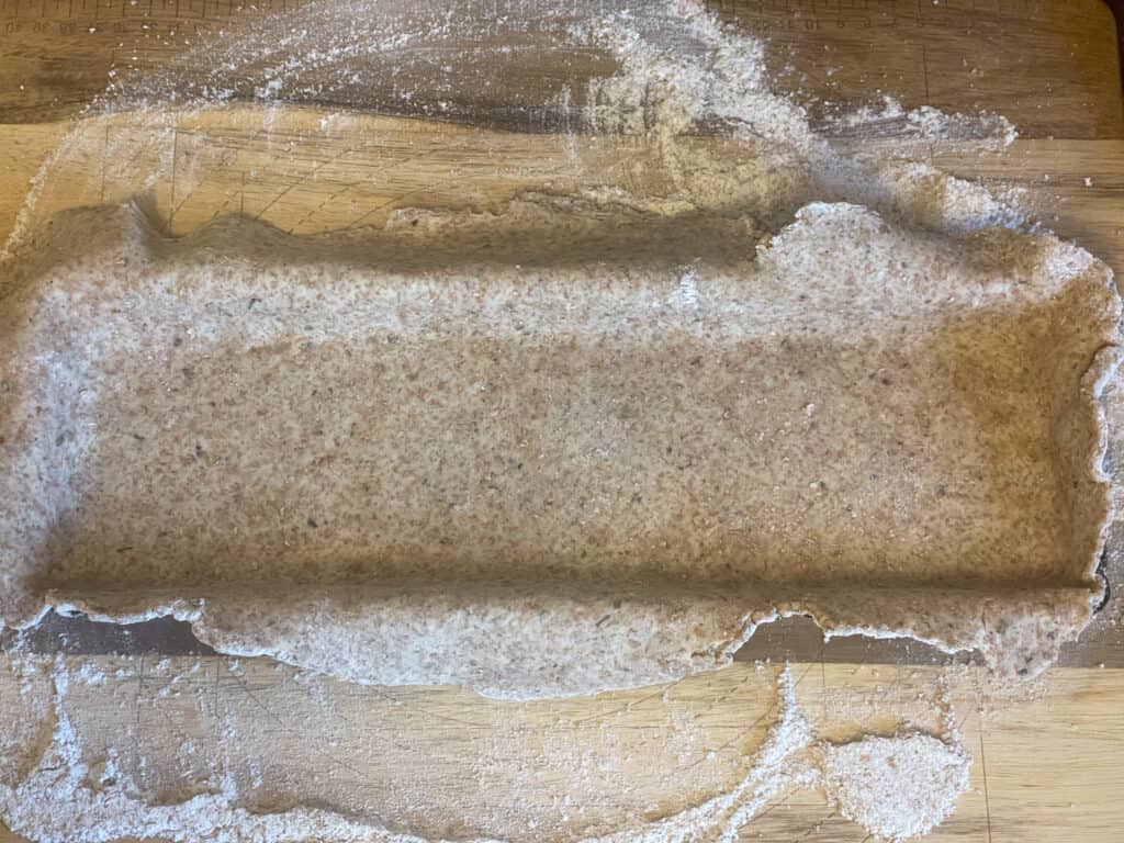 Pastry dough pressed into the pie pan and tops overhanging, on to the floured board.