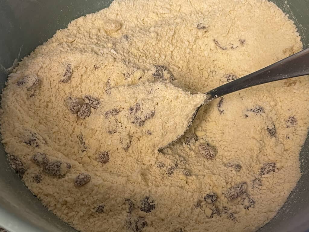 coconut rock cakes ingredients mixed in bowl with silver spoon.