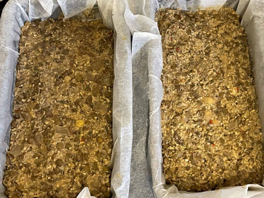 unbaked vegan meatloaf packed into 2 loaf pans with greaseproof paper lining.