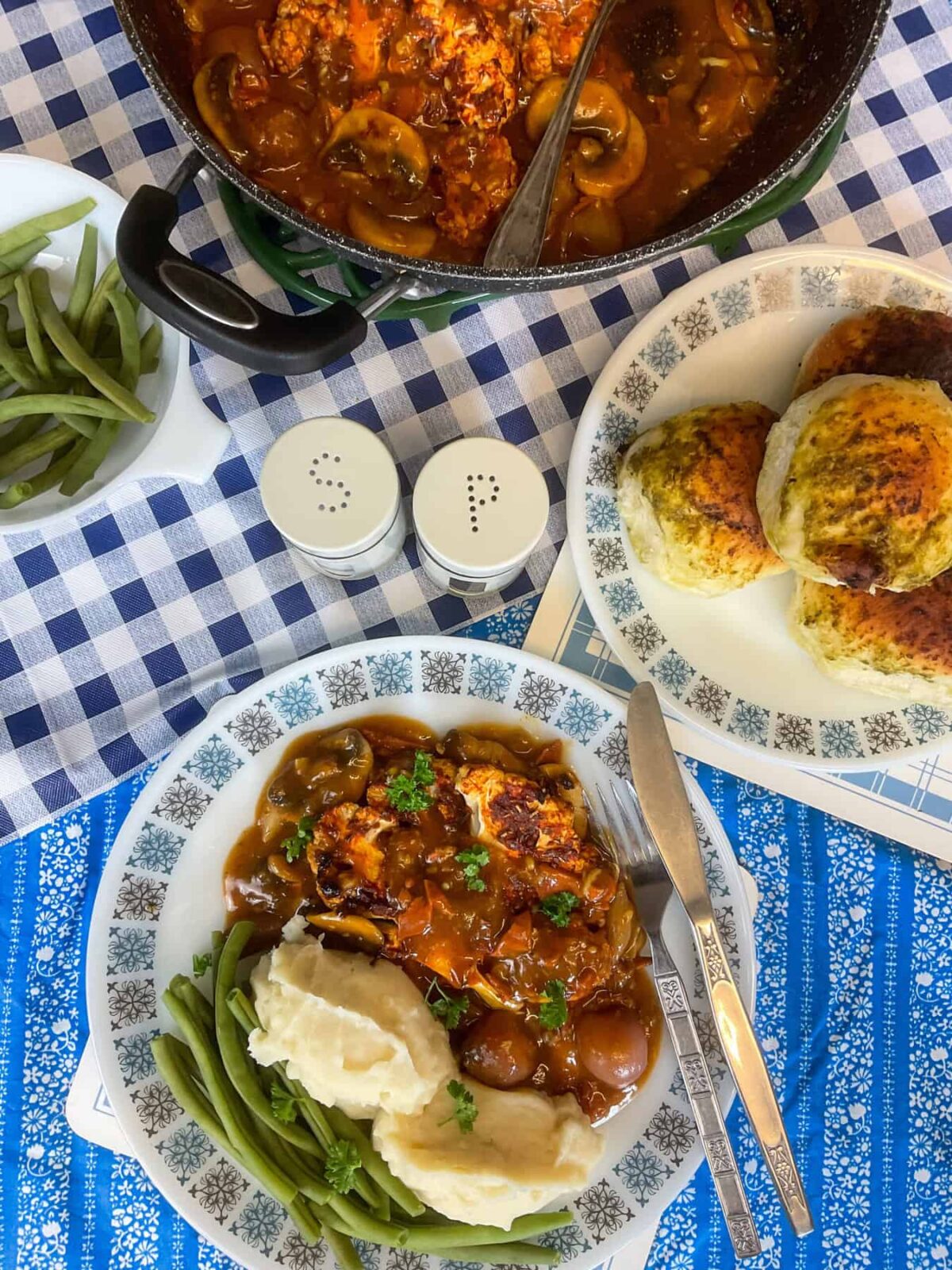 A plate of coq au vin with sides of mashed potatoes and green beans.