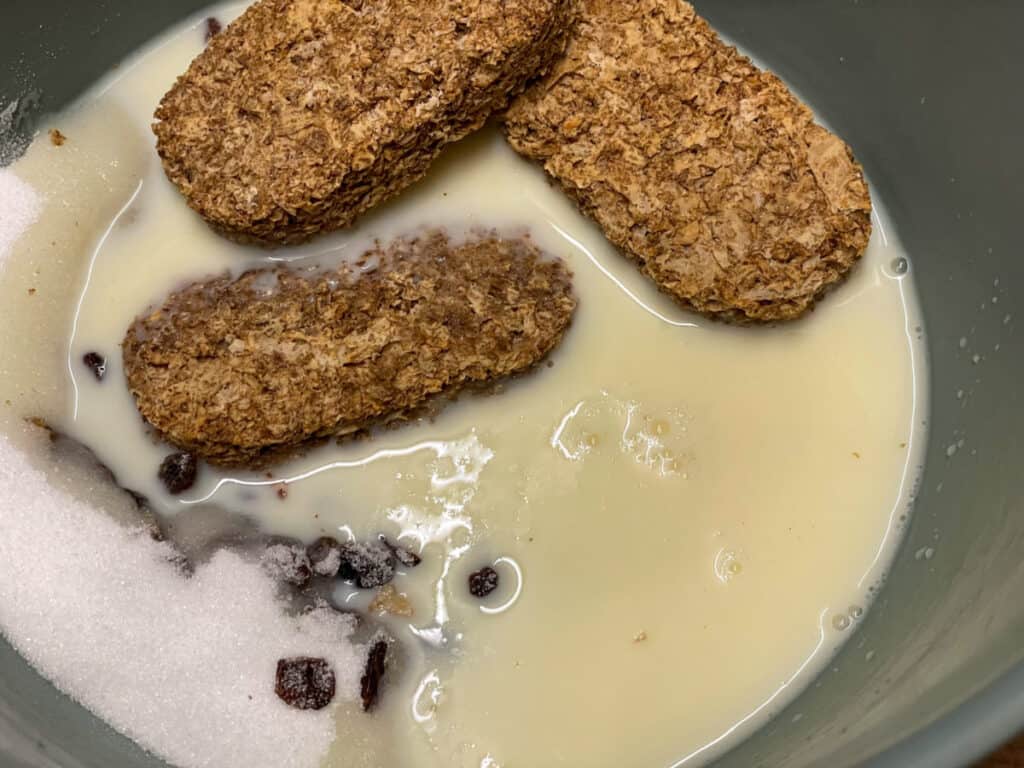 plant milk poured into Weetabix cake ingredients in blue mixing bowl.
