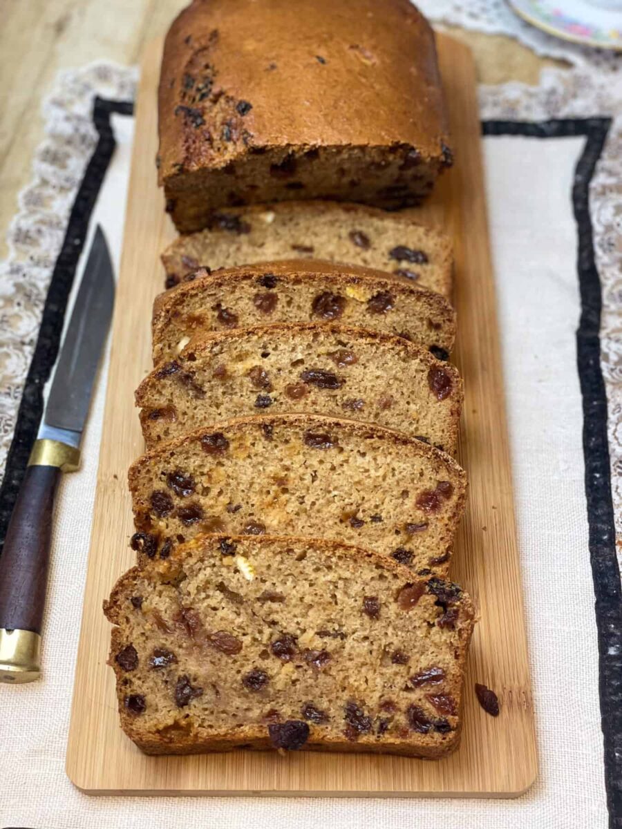Long wooden chopping board with Weetabix cake slices and large piece of cake unsliced, wooden handled knife to side, frilly linen placemat underneath, featured image.