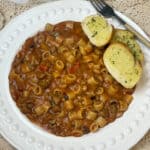 Goulash served with garlic bread, fork to side. Featured image.
