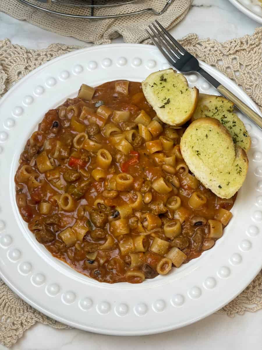 Goulash served with garlic bread, fork to side. Featured image.