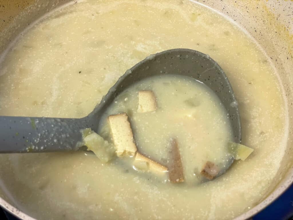 Scottish Cullen skink soup cooked and plant milk added, grey soup ladle with a scoop of soup ready to serve.