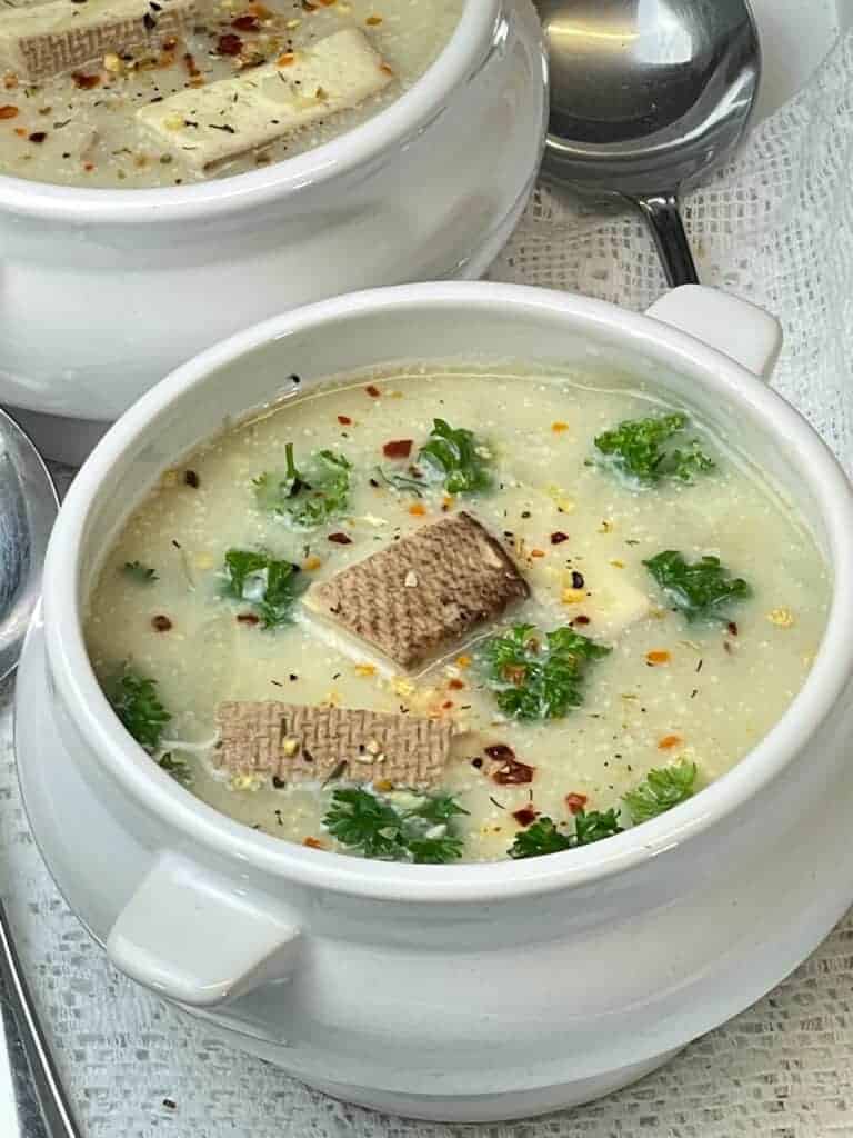 Close up of Cullen skink soup with silver spoon and white background.