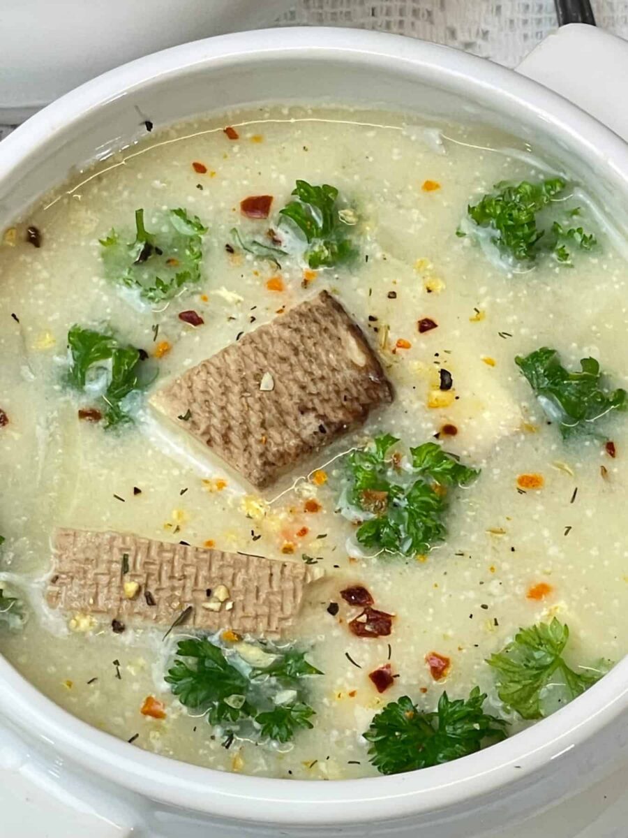Close up of bowl of vegan Cullen skink soup garnished with chopped parsley and sprinkled with herb mix.