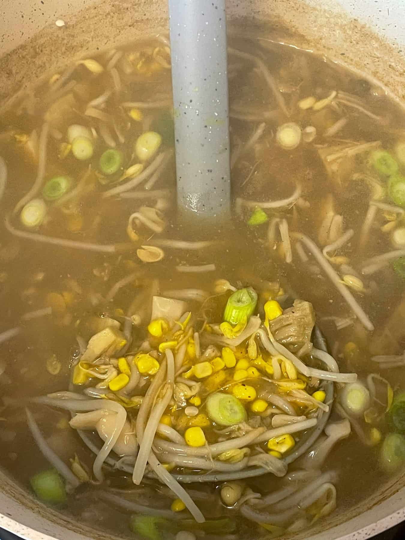 Soup cooked and ready to serve with grey soup ladle.