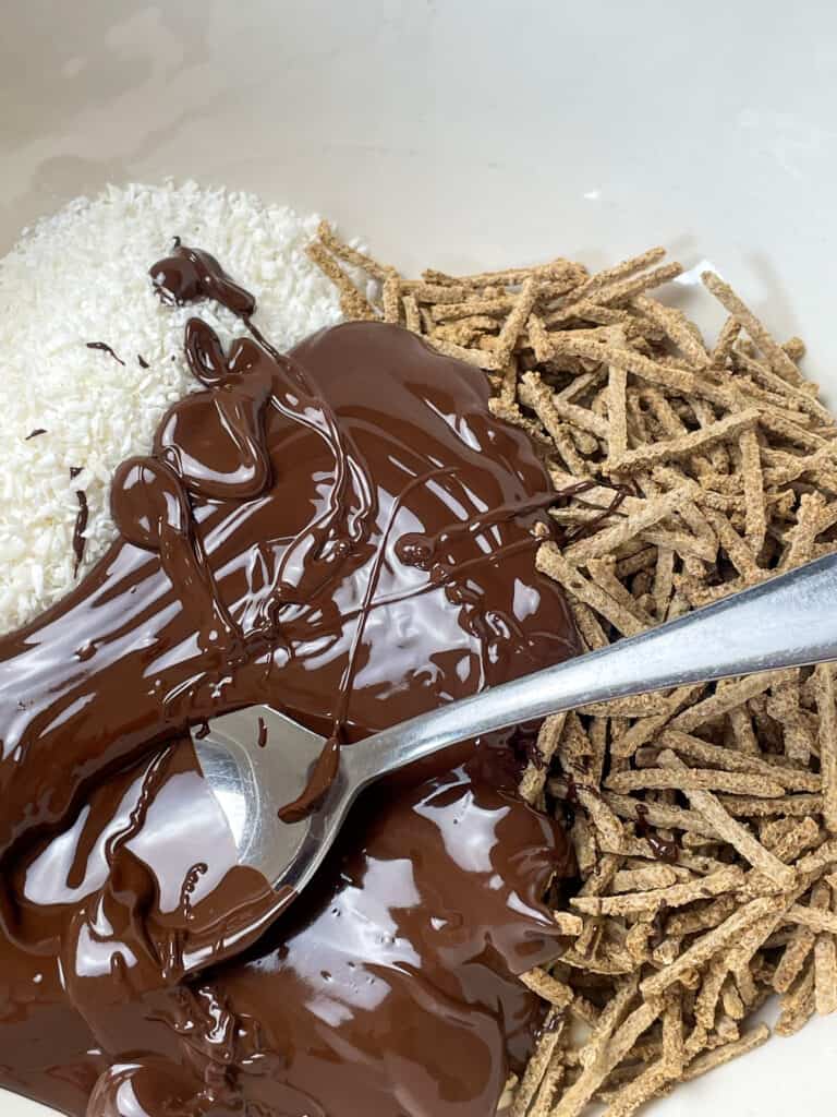 melted chocolate poured into the ingredients for ting-a-lings, silver spoon in bowl.