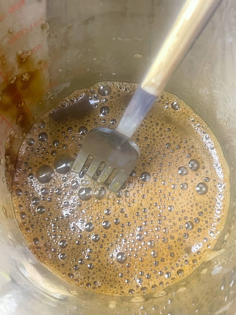 treacle and milk stirred together in a glass jug with a cutlery fork.