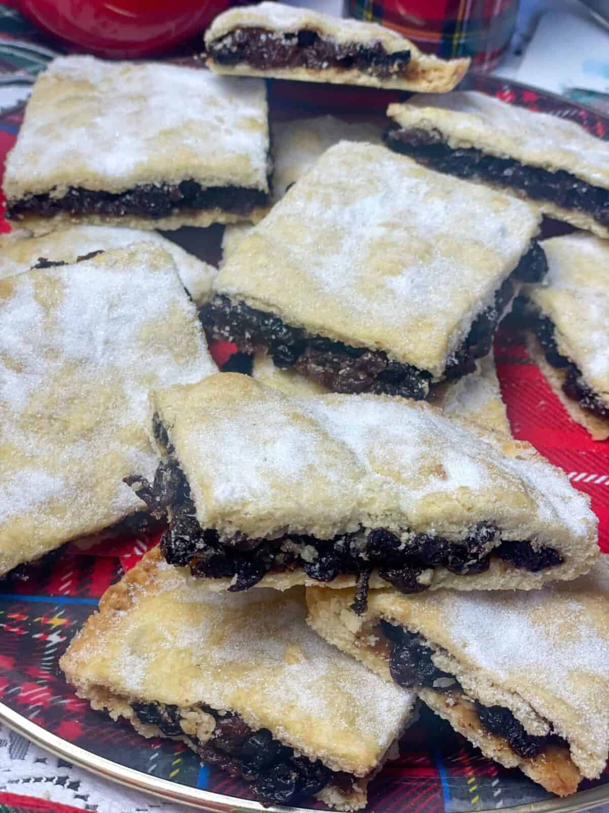 Close up image of Scottish fruit slice piled on to a tartan patterned tray with tartan cup in background.