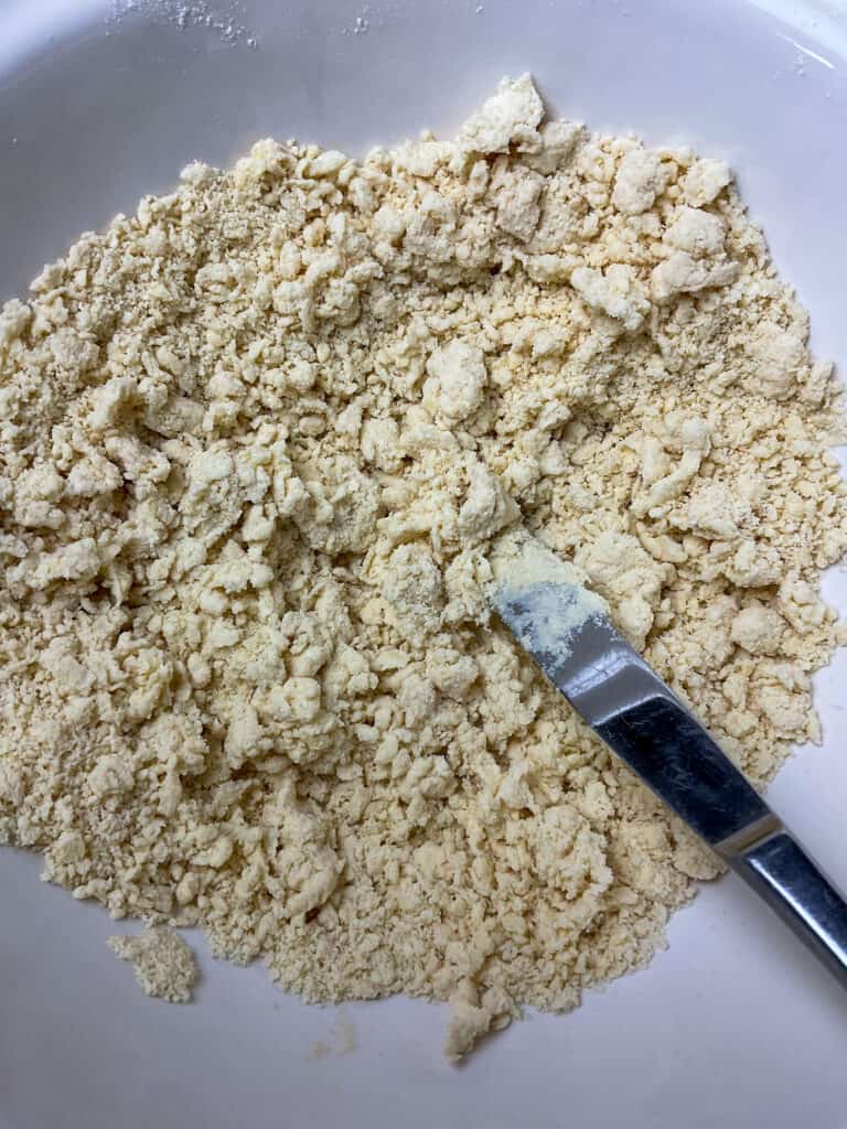 Margarine and flour mixed into breadcrumbs and water being stirred through with a small knife.
