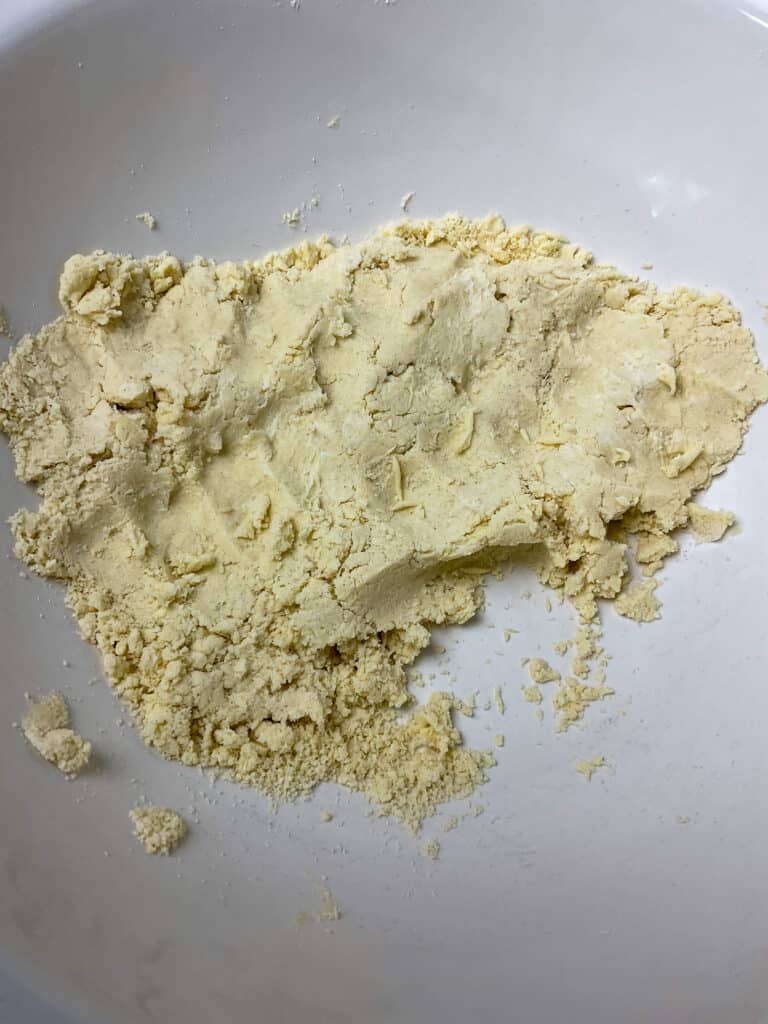 Pastry dough brought together into a clump at side of mixing bowl.