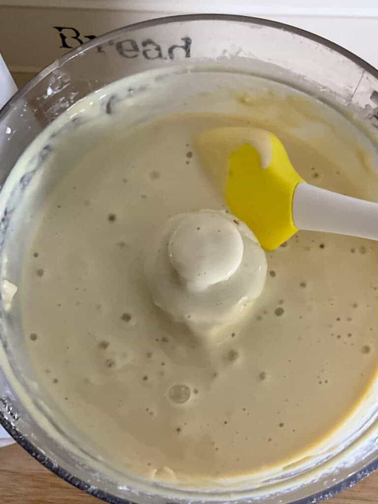 Flan filling blended smooth and being stirred with yellow spatula.