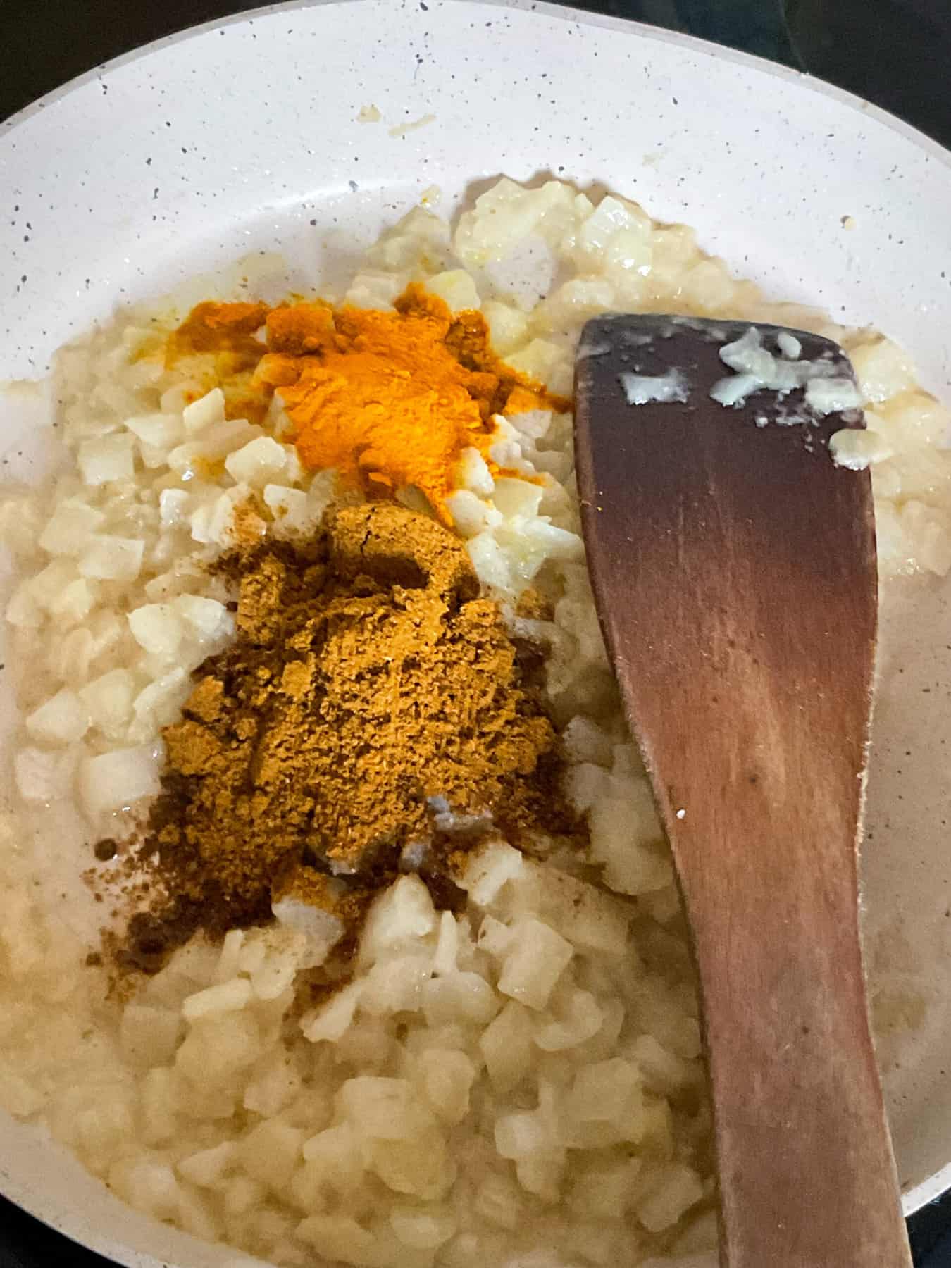 Spices added to cooked onions in fry pan.