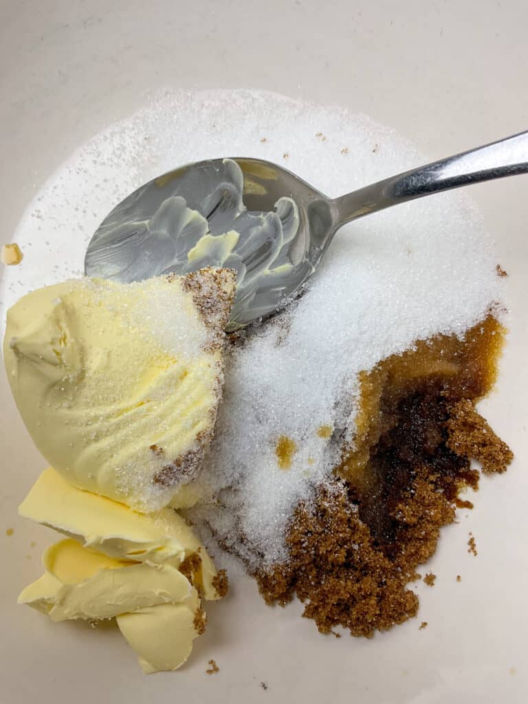 Margarine and sugar in mixing bowl with mixing spoon.