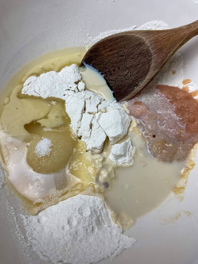 vegan steamed jam pudding ingredients in mixing bowl with wooden spoon.
