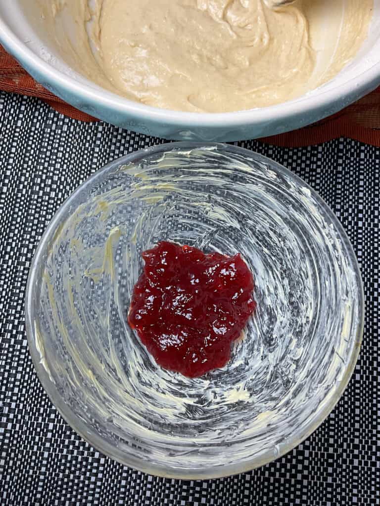 jam added to bottom of greased pudding basin with mixing bowl to side.