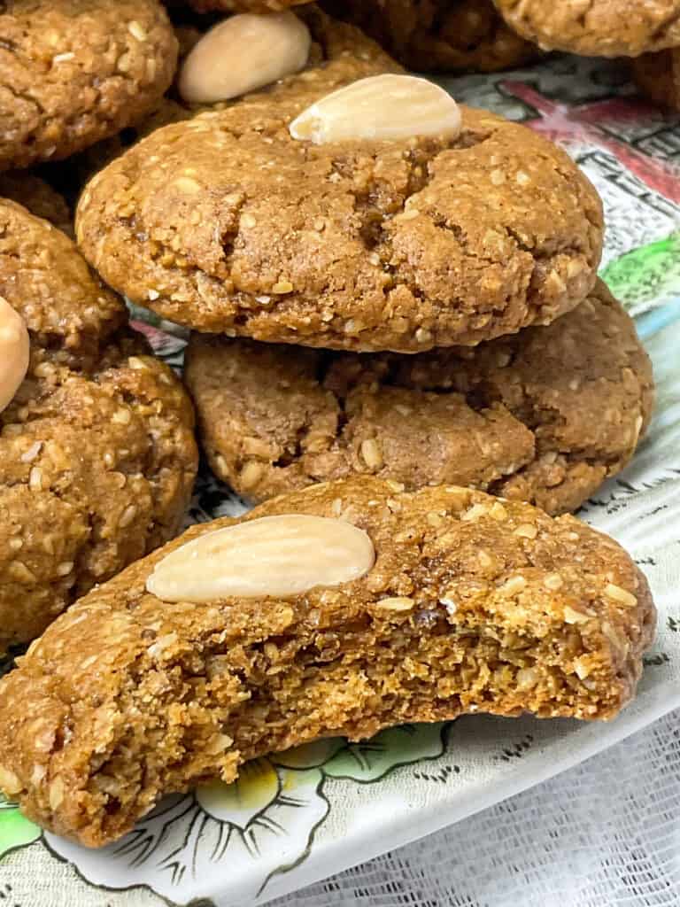 A plate of parkin biscuits with one biscuit with a bite taken out to show the inside textures.