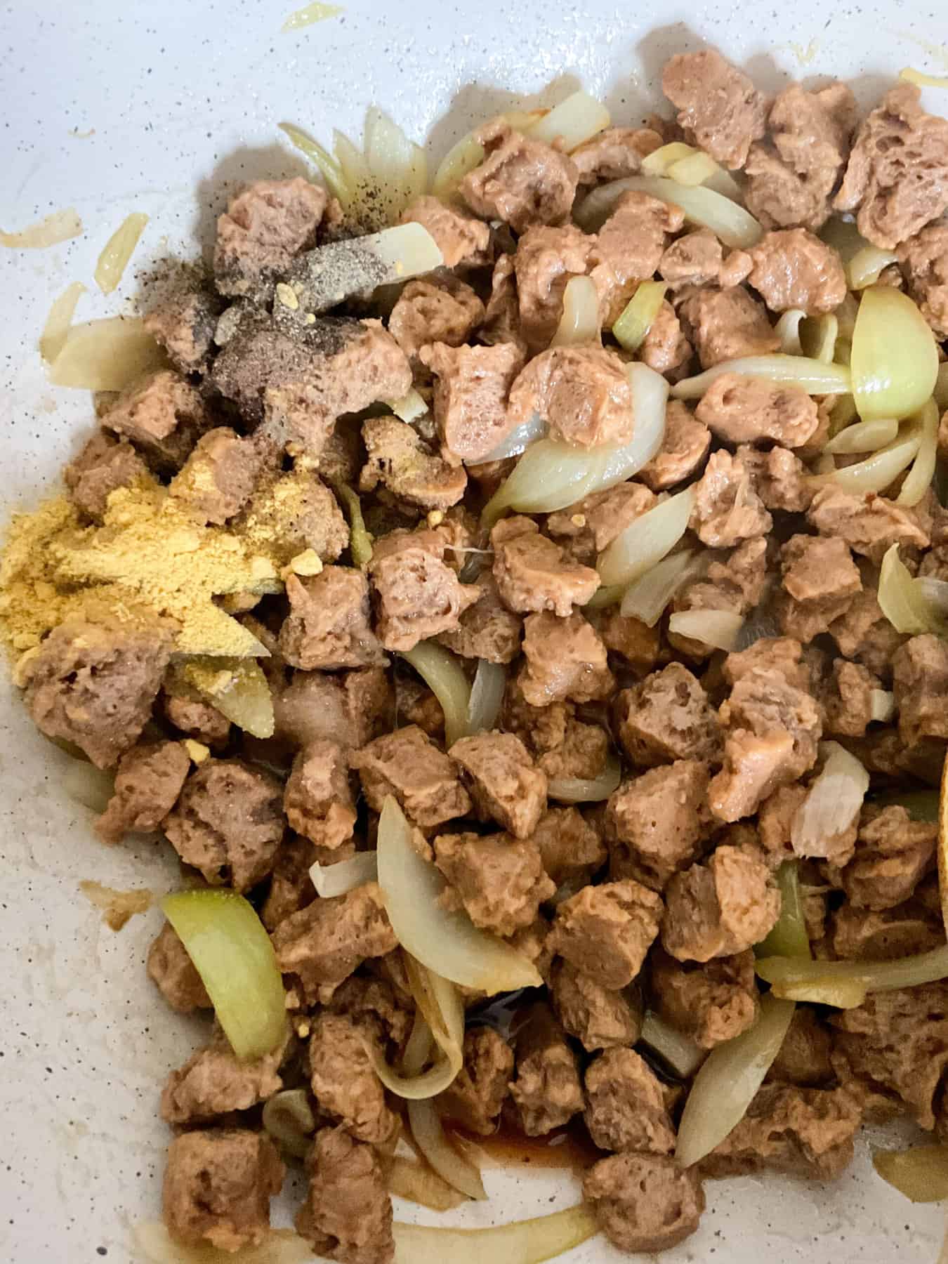 Seasonings added to TVP chunks cooking in pan.