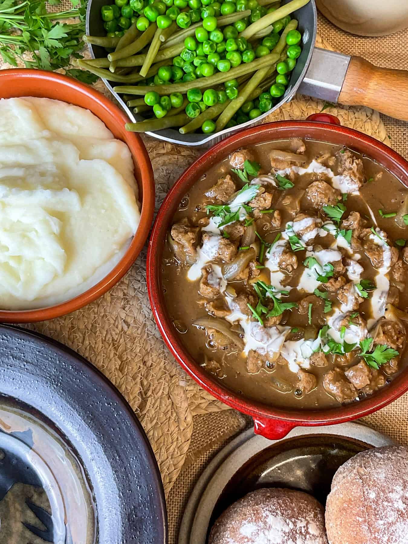 Vegan stroganoff served with mashed potatoes, peas and green beans on dinner table.