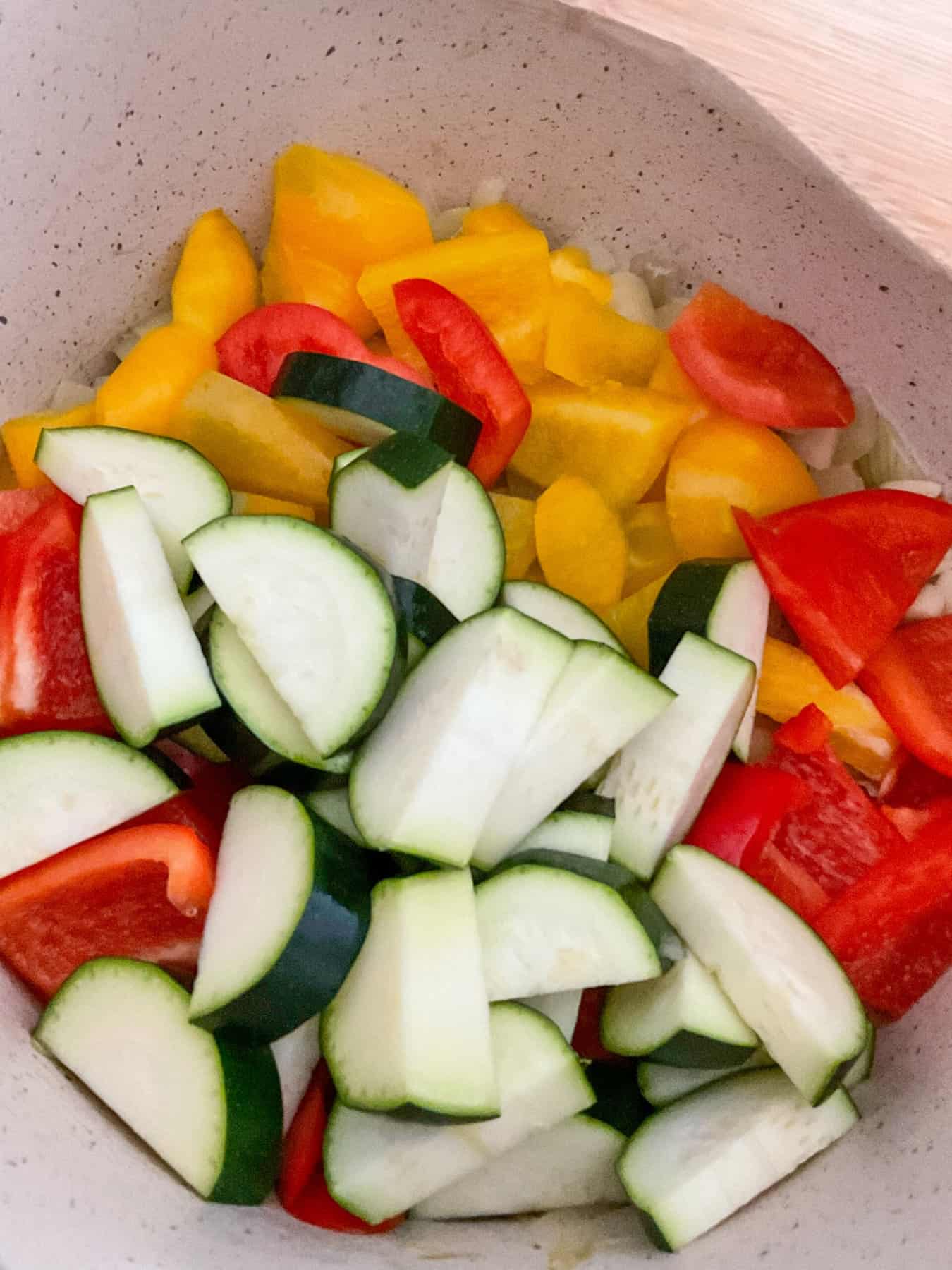 Courgette added to peppers and onions in stew pot.
