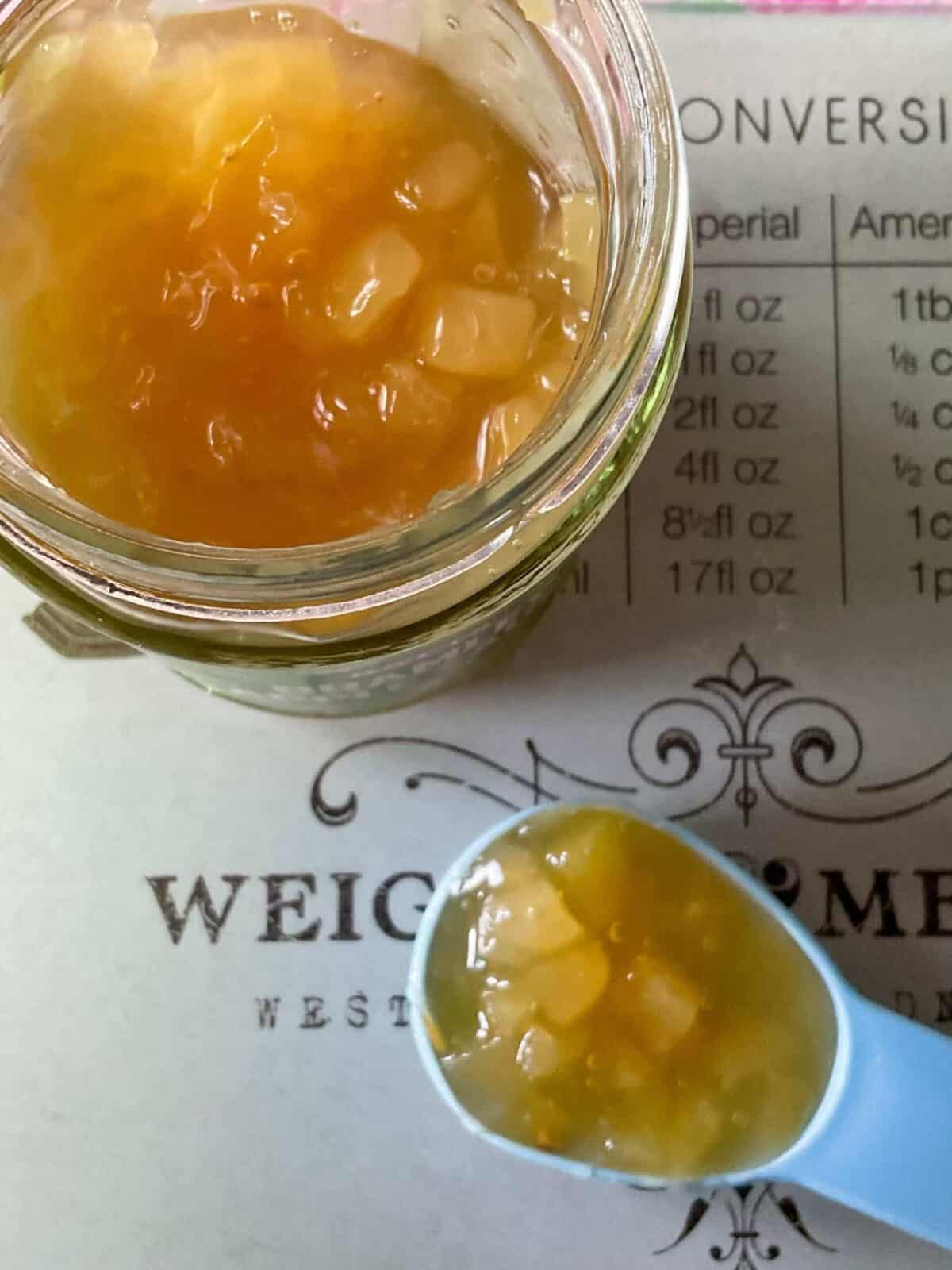 Apple sauce in a jar with a scoop of sauce on a spoon.