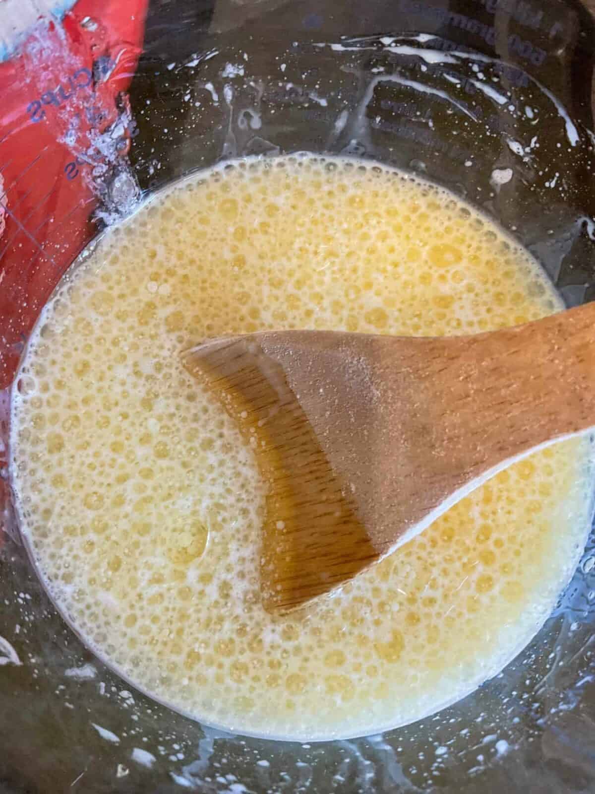Liquid ingredients stirred together in glass jug.