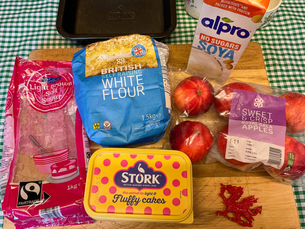 Welsh apple cake ingredients on a wooden cutting board.