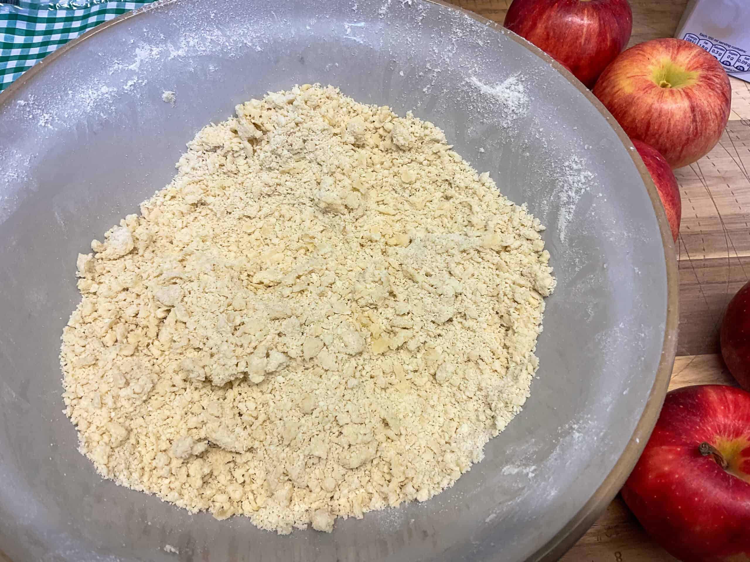 Flour mixture looking like breadcrumbs in mixing bowl.