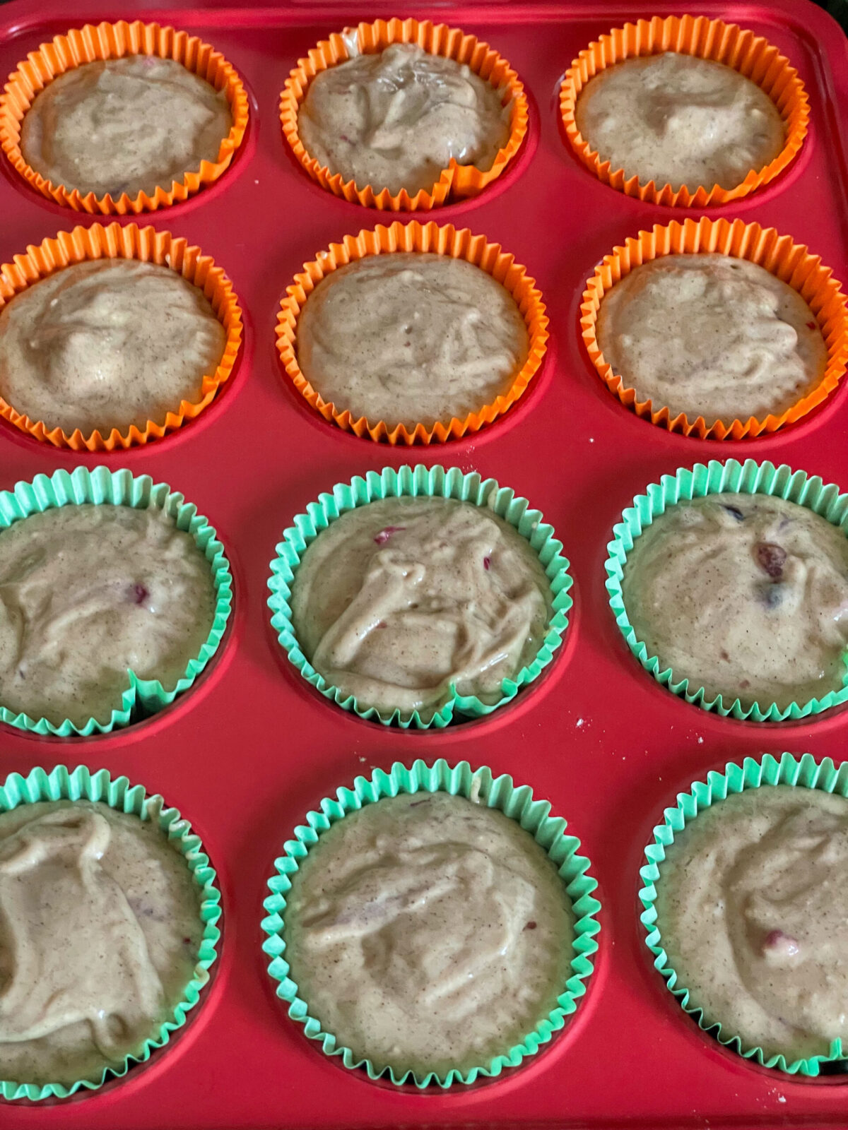 Mixed berry muffin batter divided into the muffin tray cups.