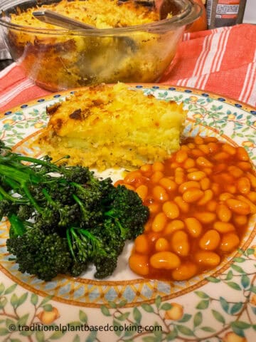 A slice of lentil pie on plate with broccoli and baked beans.