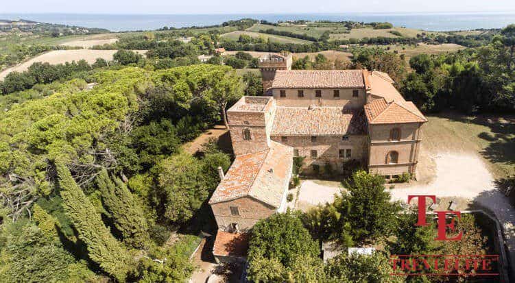 Luxurious Italian estate surrounded by lush greenery and rolling hills, with panoramic sea views in the distance. Perfect for private retreats or high-end living in Italy.