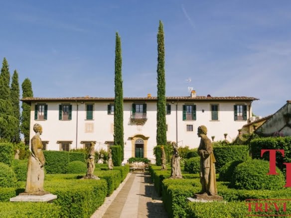 Elegant Italian villa surrounded by lush greenery and classical statues, showcasing luxurious real estate in Italy; perfect for discerning buyers seeking exclusivity.