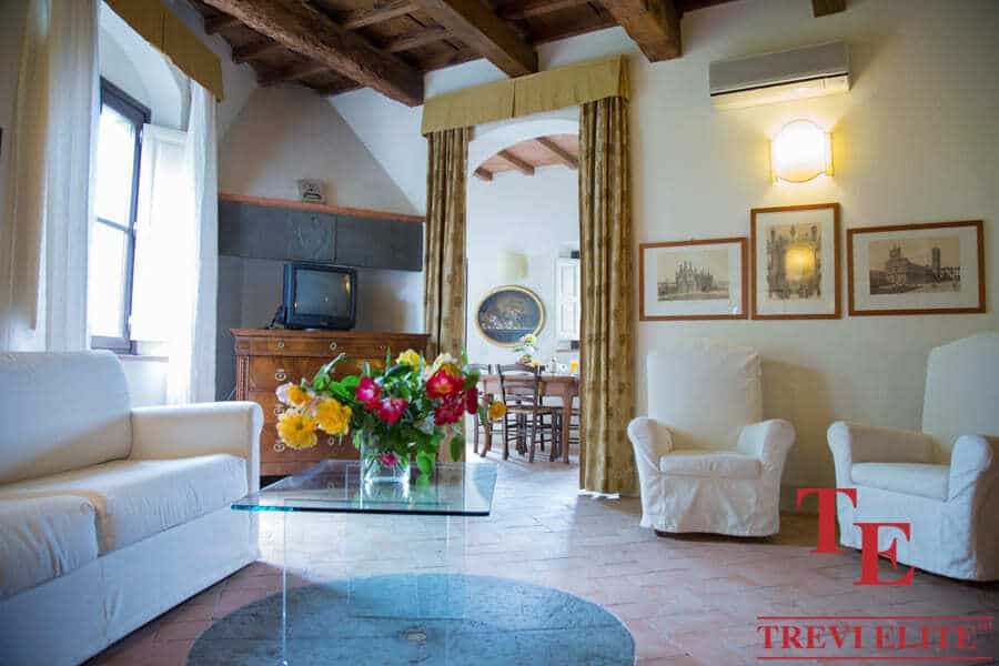 Charming Italian living room with rustic wooden ceiling beams, elegant furnishings, and classic artwork, offering a luxurious and cosy atmosphere for discerning property buyers.