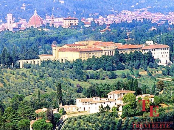 Ancient Italian estate surrounded by lush greenery and rolling hills, with historic architecture and scenic views of Florence skyline in the background.