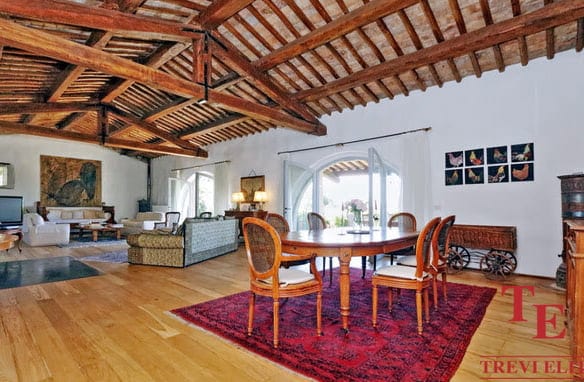 Luxurious Italian living room with exposed wooden beams, elegant furnishings, and sophisticated decor, showcasing high-end design and comfort.