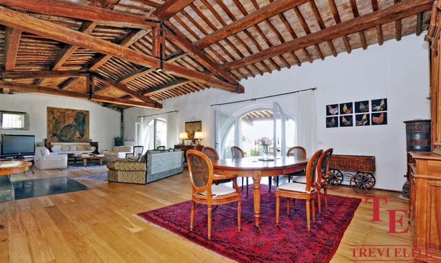 Luxurious Italian living room with exposed wooden beams, elegant furnishings, and sophisticated decor, showcasing high-end design and comfort.