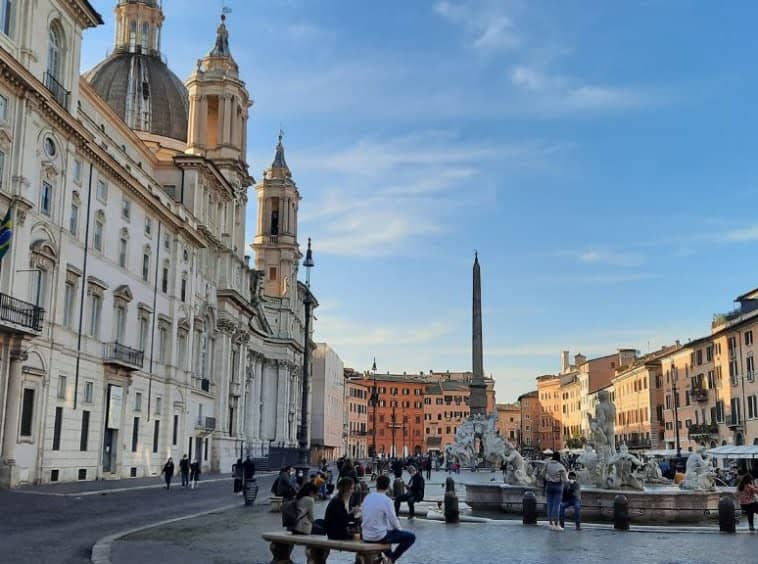 Romantic Italian city square with historic architecture, bustling crowd, and iconic fountains in Rome, Italy. Ideal for promoting luxury Italian properties offered by Trevi Elite.