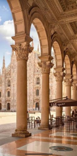 Ornate classical columns with intricate capitals under arched portico overlooking historic Italian architecture.
