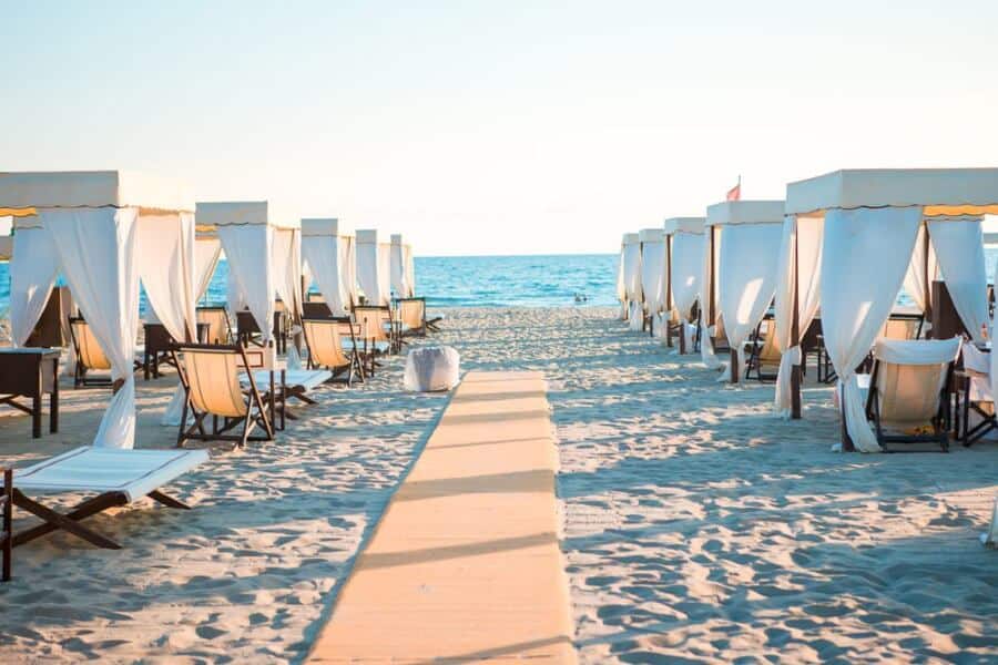 Luxurious beach cabanas with elegant drapes and sun loungers on an exclusive Italian seaside resort. Perfect for a high-end holiday experience in Italy’s finest coastal locations. For luxury connoisseurs - Trevi Elite.