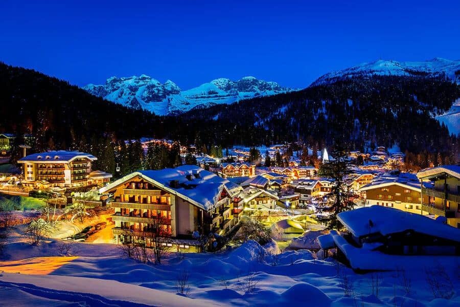 Luxury ski resort in the Italian Alps illuminated at night with snow-covered chalets and mountain backdrop. Stunning winter landscape showcasing high-end alpine living for discerning buyers. For luxury connoisseurs - Trevi Elite.